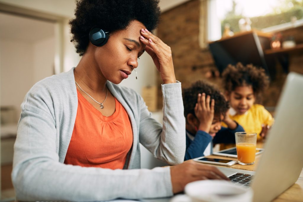 Black single mother feeling frustrated while working at home.